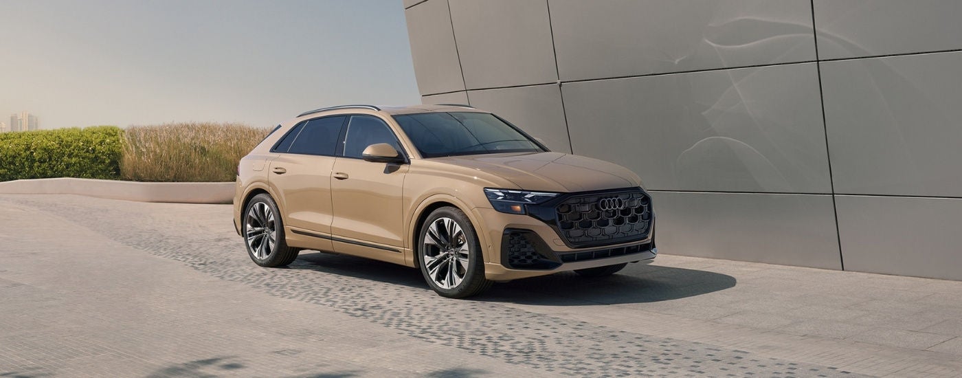 A tan 2024 Audi Q8 parked near a wall.